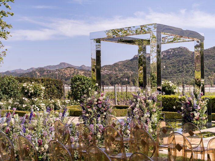 he lawn at Mizel Estate transformed into a glamorous enchanted forest wedding ceremony, featuring a mirrored aisle, mirrored altar, and clear ghost chairs.