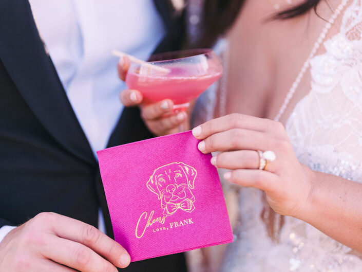 Hot pink custom cocktail napkin featuring a gold stencil of the couple’s dog, adding a personal and playful touch to the event.
